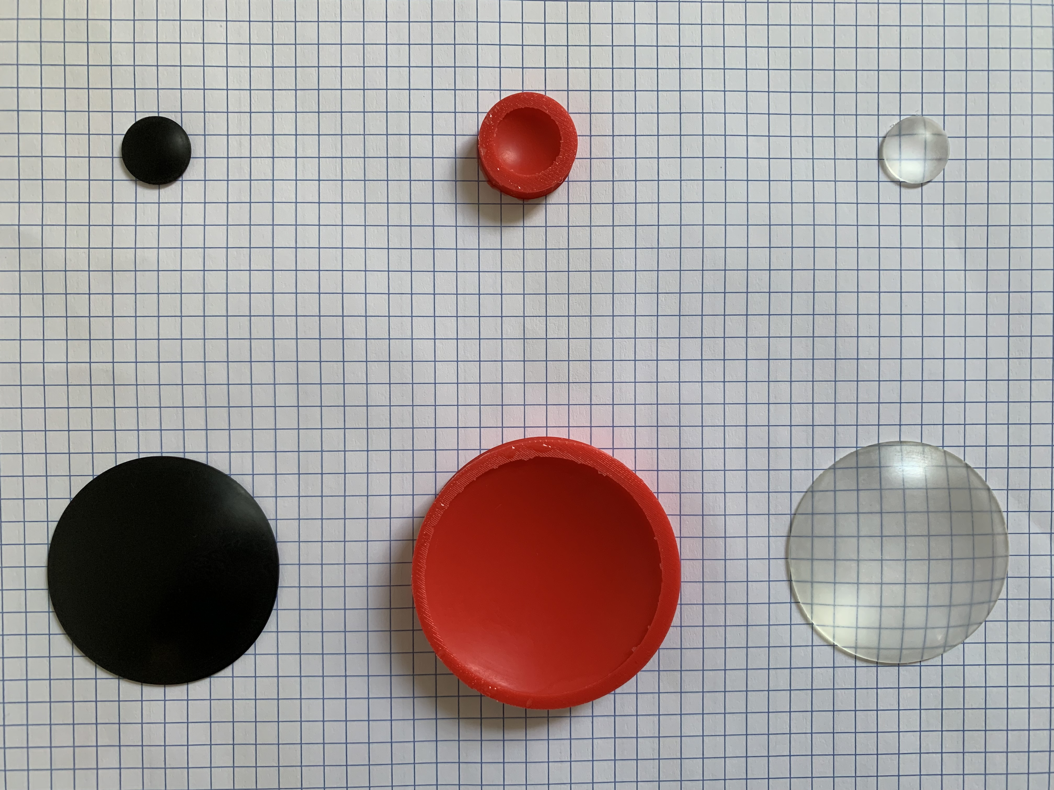 Photograph of a large and a small lens in each
            of three stages: polished, 3D-printed blank; silicone mold;
            and finished epoxy resin lens