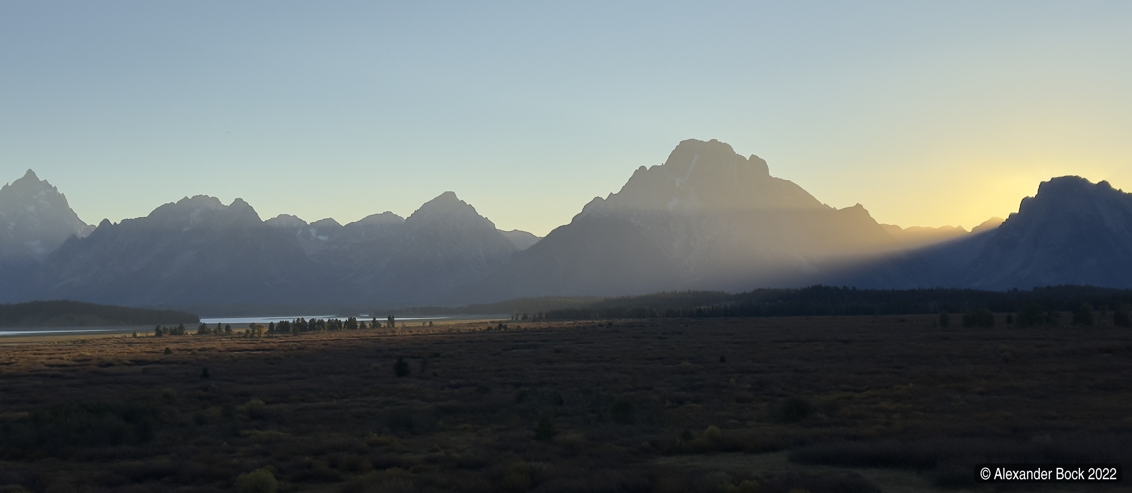 View of the sun setting behind the Tetons